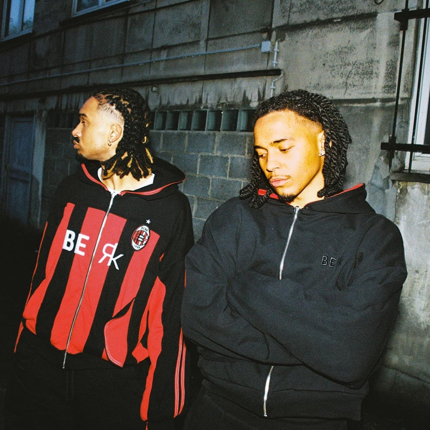 Two figures in the racing-stripe jacket and hooded outerwear